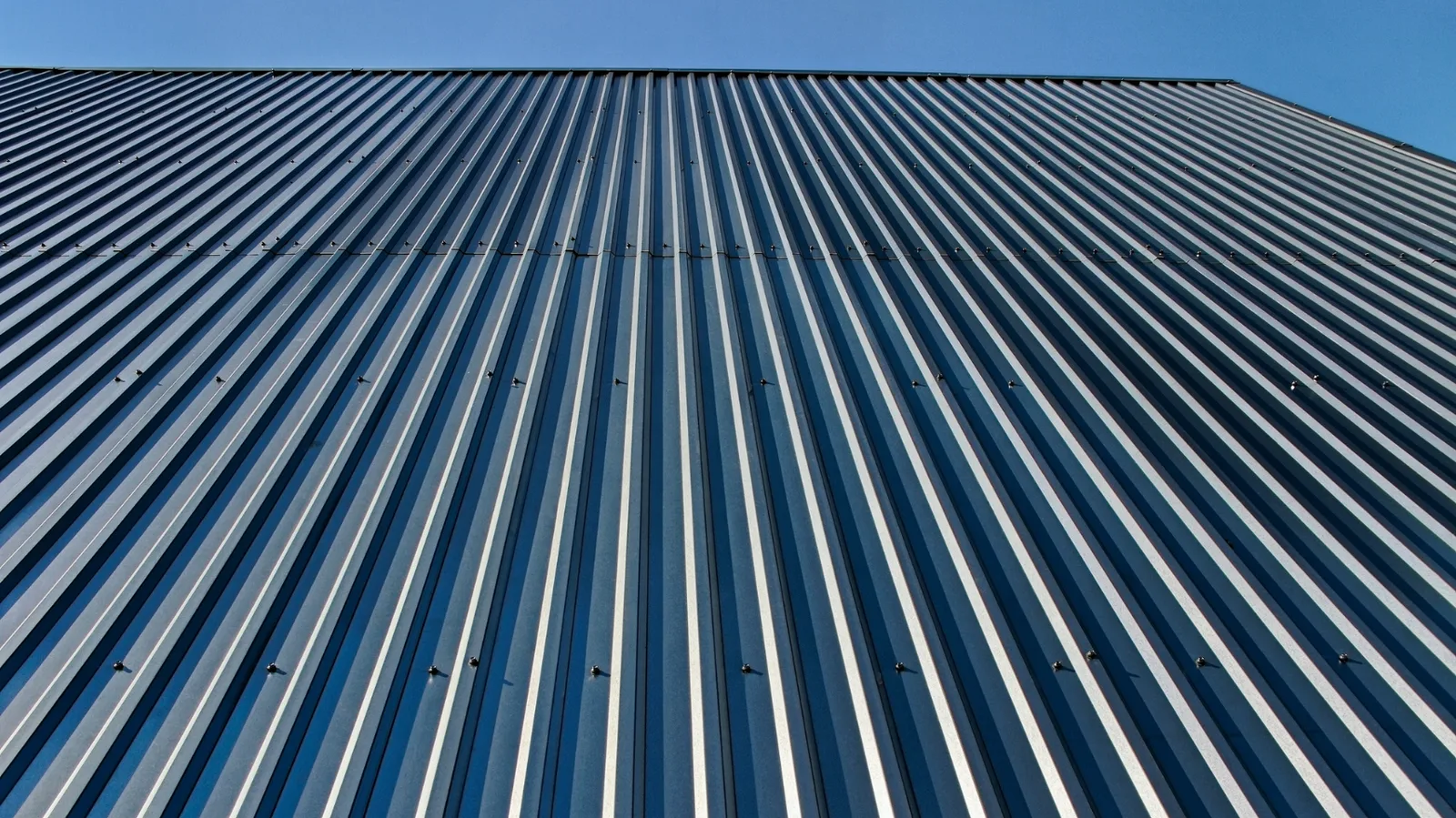 Upward view of ribbed metal cladding against a clear sky